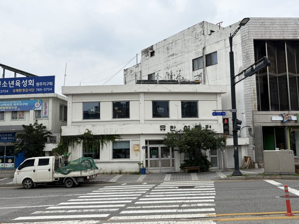 “Limited Coffee exterior, an old two-story building with a vintage barbershop sign, in Wonju”