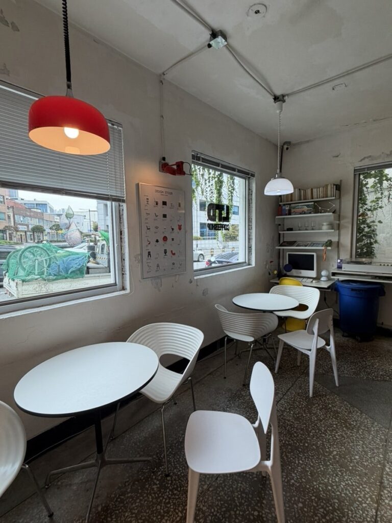 Modern seating area at Limited Coffee with white round tables, designer chairs, and hanging plants